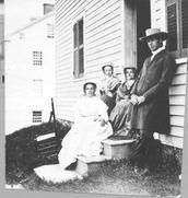 SA0155 - Photo shows Elder Robert Wagan, a chair maker, and South family sisters.  The women are seated on the steps of a building.  Left to right: Ann Charles, Katie Boyle, Polly Lewis., Winterthur Shaker Photograph and Post Card Collection 1851 to 1921c
